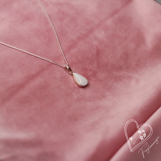 dråpeformet smykke minnesmykke dråpe morsmelksmykke i sølv med rosa bakgrunn